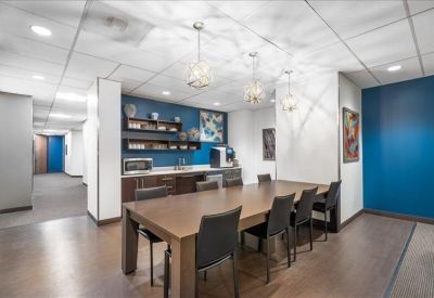 Modern communal kitchen and dining area with blue walls and pendant lighting.