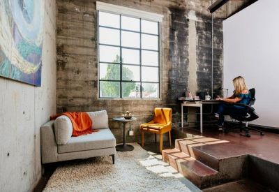 Quiet breakout nook with a grey sofa, orange throw, and a small side table.