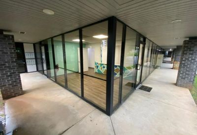 Spacious reception area with floor-to-ceiling glass walls and modern wood flooring.