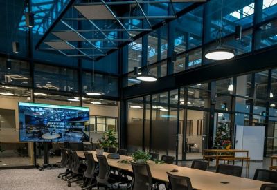 Spacious boardroom with a long wooden table under an industrial-style glass ceiling.