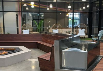 Communal lounge area featuring a modern fire pit, tiered wooden seating, and hanging egg chairs.