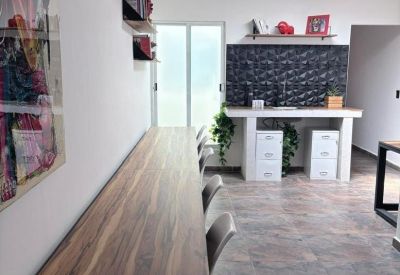 Long wooden shared desk area with grey chairs and a whiteboard.