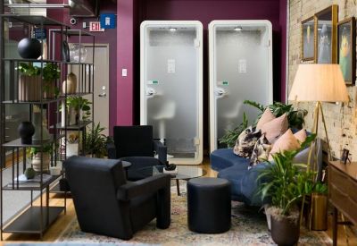 Lounge area with navy blue velvet chairs, privacy phone booths, and vibrant purple walls.