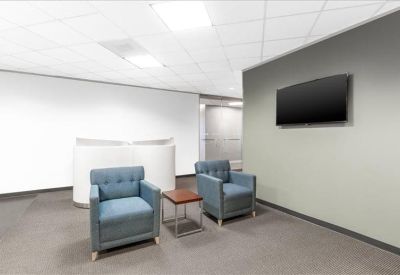 Modern lobby lounge area with blue armchairs and a wall-mounted monitor.