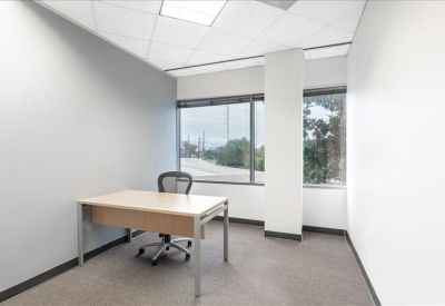 Small private office with a single desk and a large window.