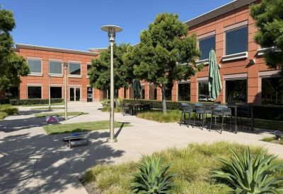 Outdoor communal courtyard with seating areas, large planters, and a green umbrella.