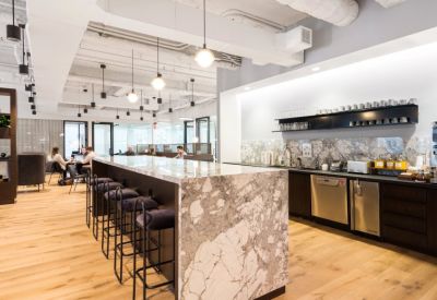 Kitchen and breakout area with a large marble island, velvet bar stools, and a built-in coffee station.