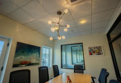 Bright boardroom with minimalist art and views into the main workspace.