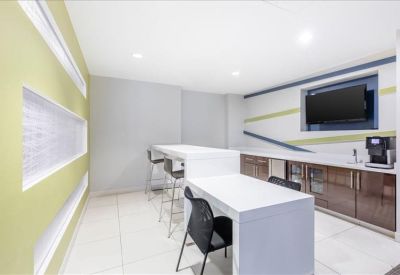 Modern breakroom area with a white kitchen island and coffee machine.