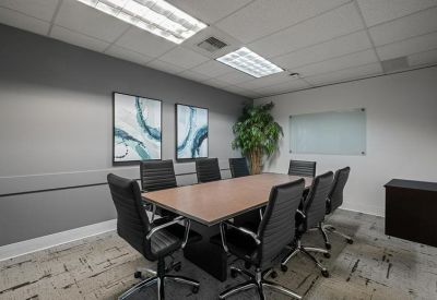 Large conference room with a wooden table, black leather chairs, and a potted plant.