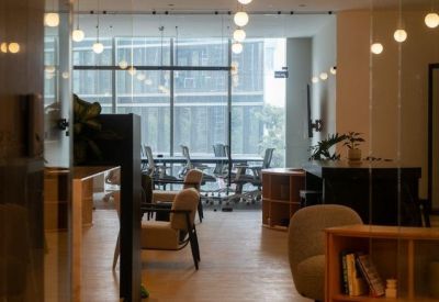 Entrance to a coworking area with globe pendant lights and a wooden bookshelf.