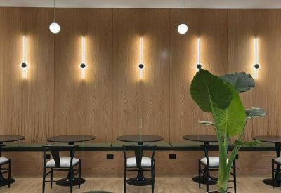 Cafe-style seating area featuring a long cushioned bench, round tables, and warm wall lighting.