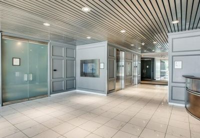 Modern lobby with grey paneled walls, a slatted metal ceiling, and polished tile flooring.