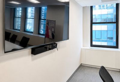 Large TV in meeting room with chairs and window.
