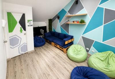 Vibrant breakroom featuring a geometric blue wall, blue sofa, and green bean bag chairs.