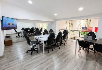 Collaborative area with white tables, black chairs, and a view into a balcony with plants.