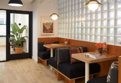 A cozy breakout nook with dark blue booth seating, wooden tables, and a decorative glass block wall.