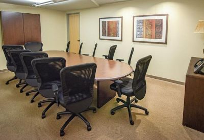 Large meeting room with an oval wooden table and black mesh chairs.