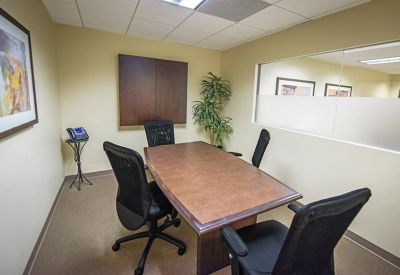 Private office suite with a wooden table and frosted glass wall.