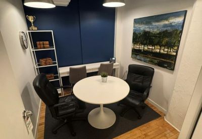 Small three-person internal office with a round white table and blue accent wall.