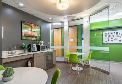 Office kitchen and break area with lime green chairs and a white bistro table.