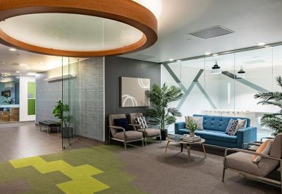 Modern reception lounge with a large circular light fixture and blue sofa.