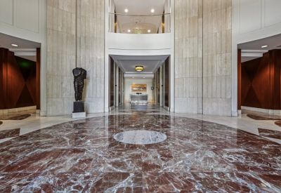 Grand marble lobby featuring high ceilings, a bronze statue, and polished stone flooring.