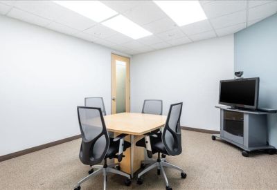Breakroom kitchen featuring a blue backsplash, wood-finish cabinets, and high-top seating.