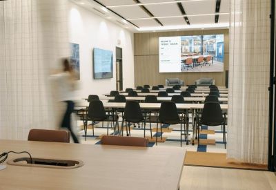 Large training room with rows of black chairs and a large presentation screen.