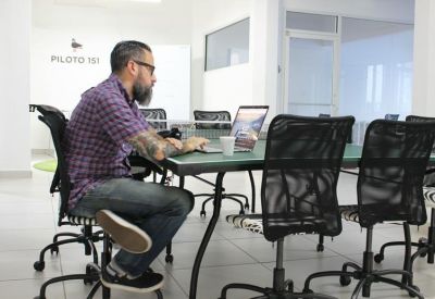 Coworking space with a man working on a laptop at a large communal table.