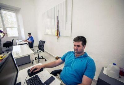 Spacious white office with multiple desks and a person working at a computer.