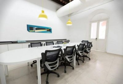 Modern conference room with a long white table and black ergonomic chairs.