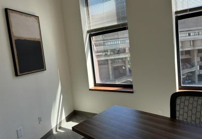 Private corner office with dark wood desk and framed abstract art.