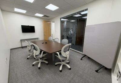 Meeting room with a central table, ergonomic chairs, and a whiteboard.