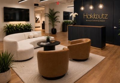 Modern reception area with a dark wood desk, white curved sofa, and branded feature wall.