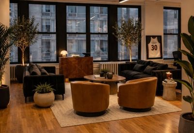 Lounge area featuring tan leather armchairs and large windows with city views.