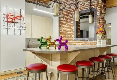 Communal kitchen area with a high breakfast bar, red stools, and whimsical balloon dog sculptures.
