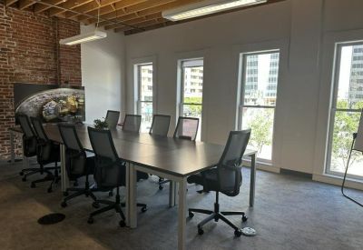 Long conference table in a meeting room with large windows and exposed ceiling beams.