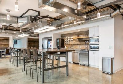 Spacious communal kitchen and break area with high-top seating and exposed industrial ceilings.