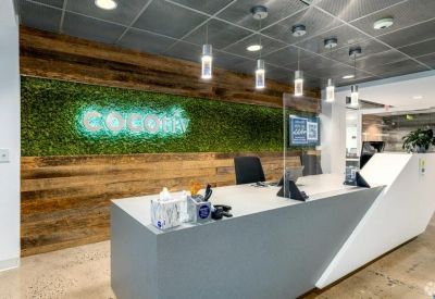 Modern reception desk featuring a vibrant green moss wall with glowing neon signage.