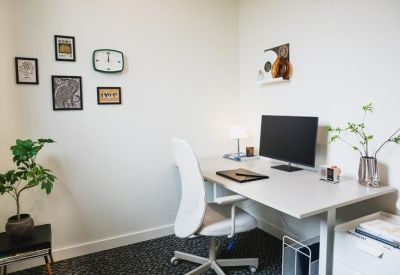 Private office with white desk, ergonomic chair, and wall art.