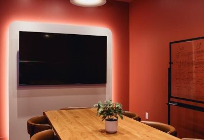 Meeting room with large wooden table, brown leather chairs, and red walls.
