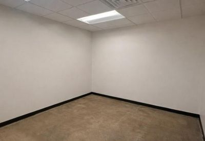Interior shot of a small private office featuring white walls and industrial-style concrete flooring.