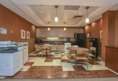 Office kitchen and breakroom with café seating, wood-look flooring, and coffee station.