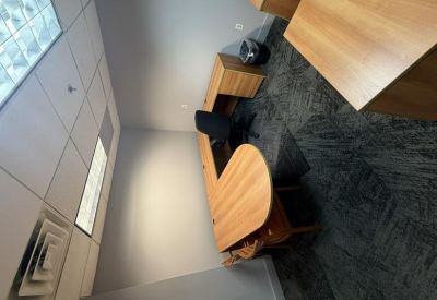 Private office featuring a curved wooden desk and grey patterned carpet.
