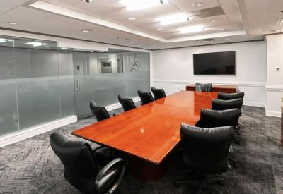 Professional boardroom with a wall-mounted screen and long wooden table.