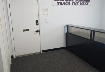 Reception entrance featuring a white door and branded wall signage.