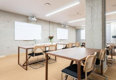 Classroom-style training room with wooden desks, woven chairs, and whiteboards.