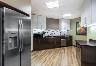 Modern breakroom kitchen with dark cabinetry, stainless steel appliances, and wood-style flooring.