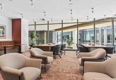 Lounge area with plush armchairs, wooden tables, and large windows.